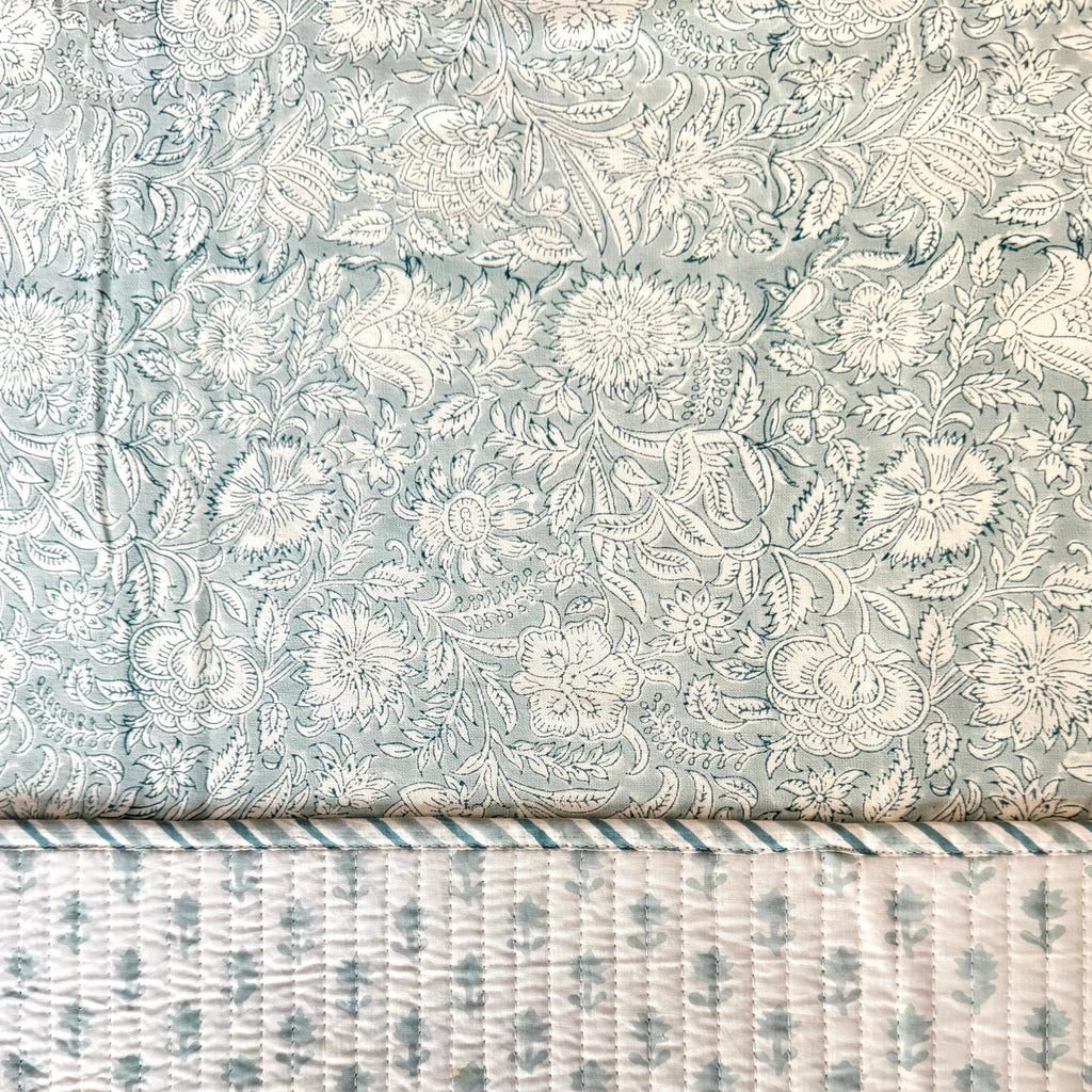 Floral patterned placemat on top of floral patterned table cloth. 