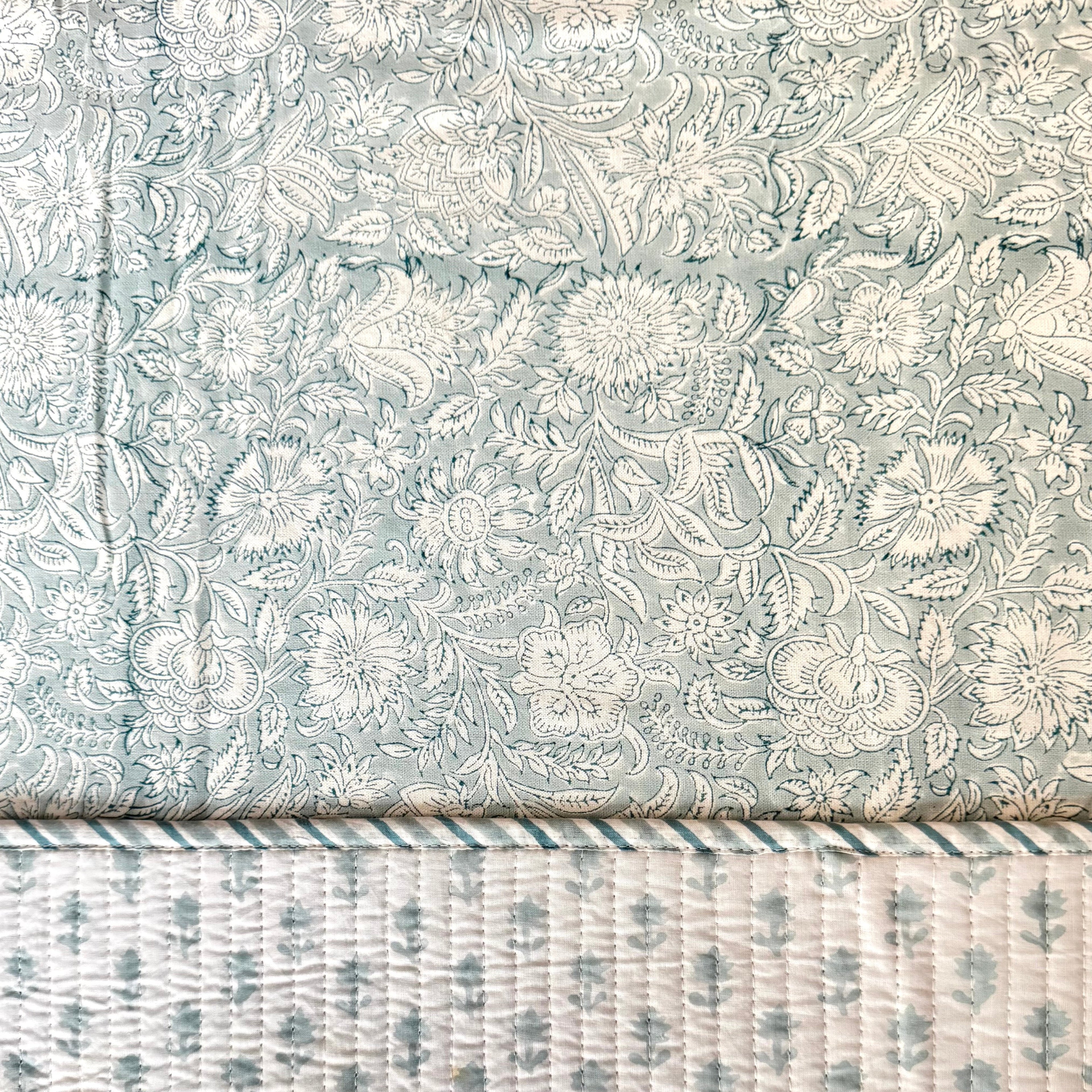 Floral patterned placemat on top of floral patterned table cloth. 