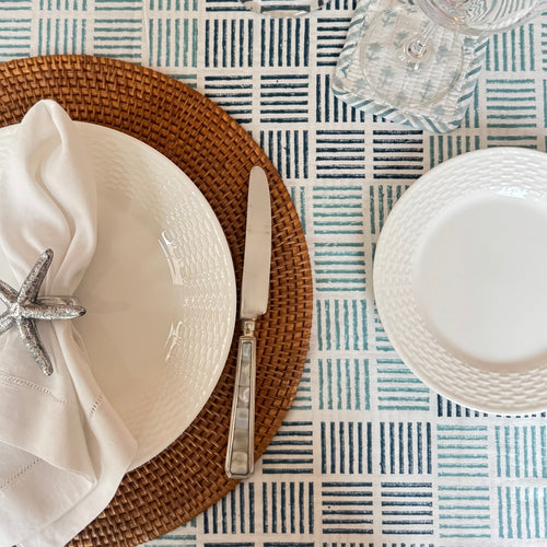 Table setting with white plates, napkin, and starfish napkin ring on a patterned tablecloth.